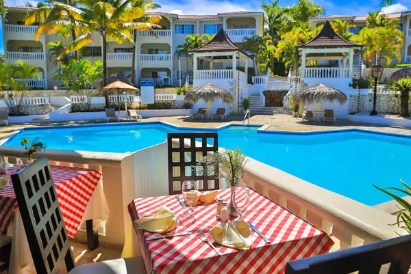 Poolside dining setup with palm trees and resort villas